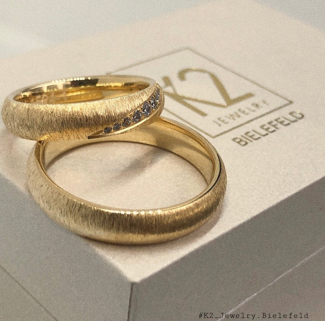 Goldene Eheringe in Bielefeld mit Diamanten die auf einer K2 Jewelry Schatulle liegen. 