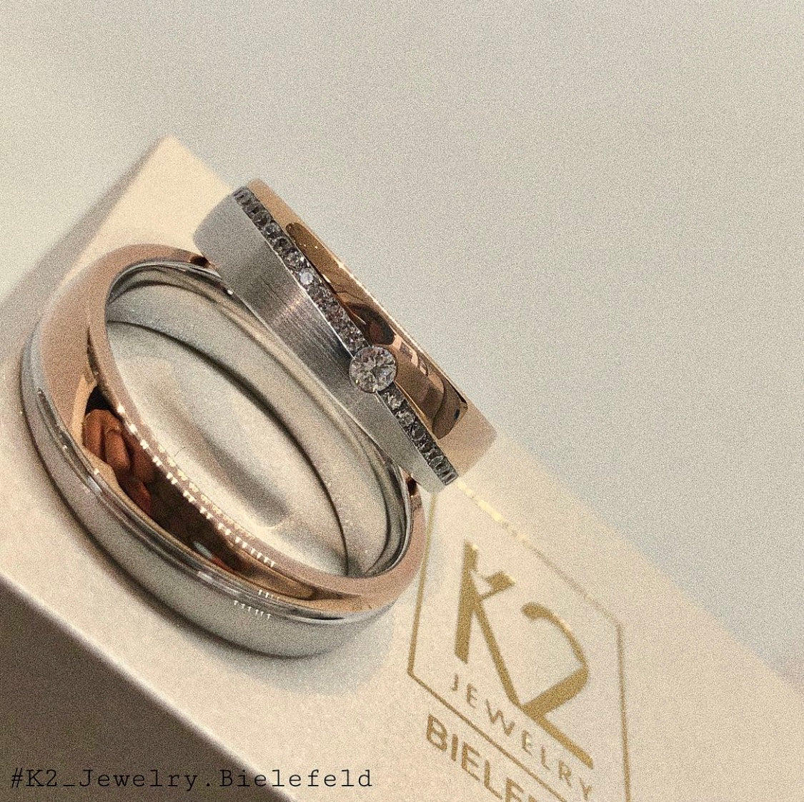 Bicolor Eheringe aus Roségold und Weißgold die auf einer K2 Jewelry Schatulle liegen.