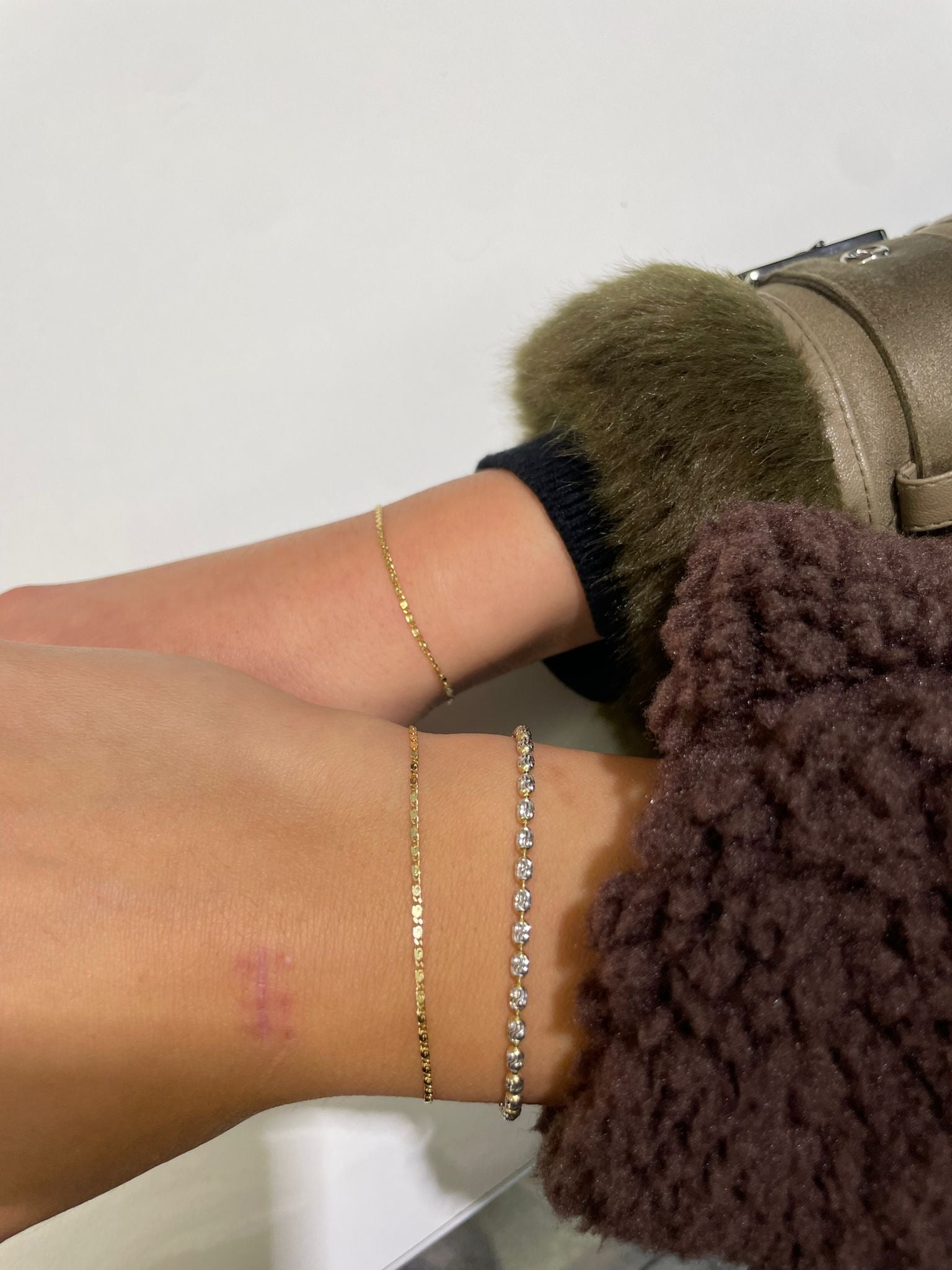 Zwei Hände präsentieren ihre goldenen Permanent-Armbänder in Bielfeld K2 Jewelry.