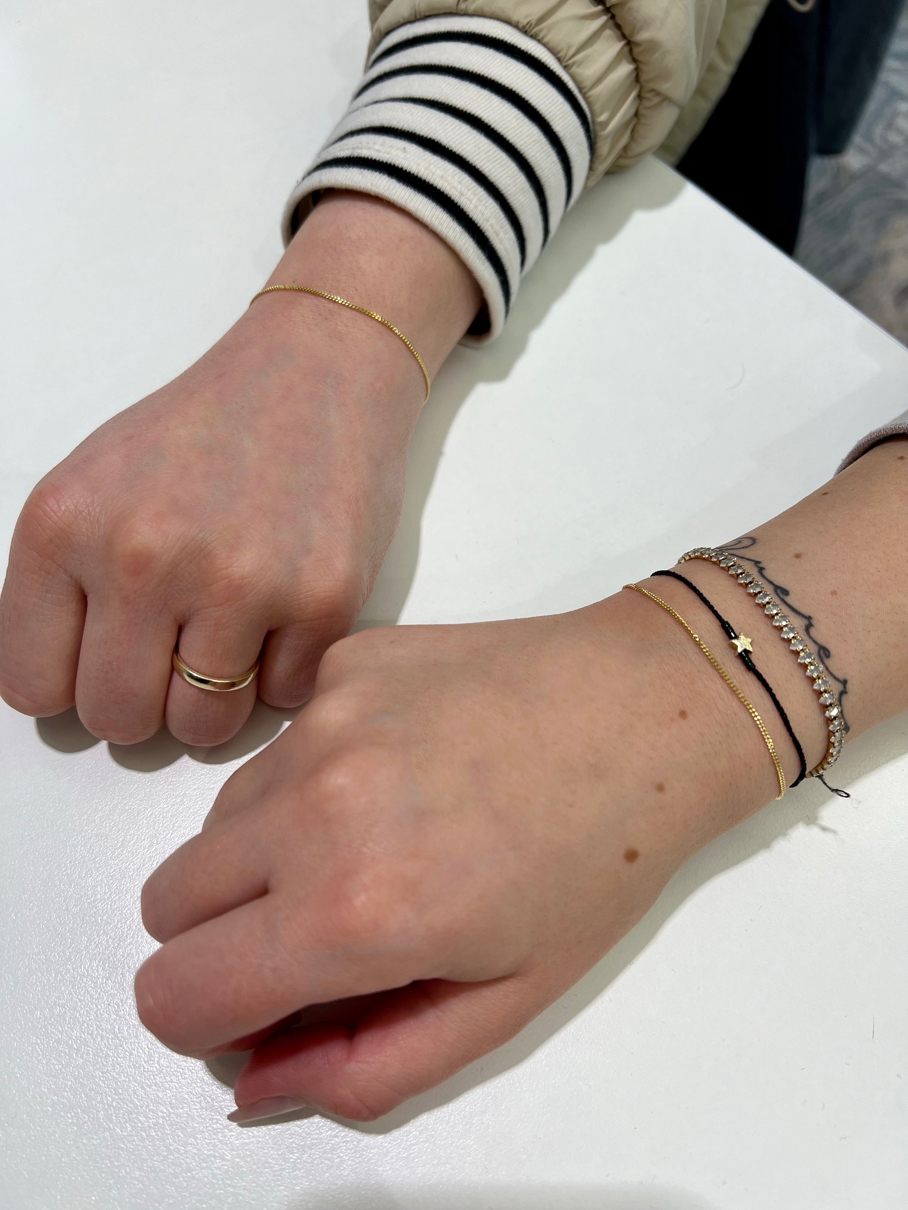 Zwei weibliche Hände dir ihre neuen goldenen Permanent-Armbänder, in Bielefeld K2 Jewelry zeigen.